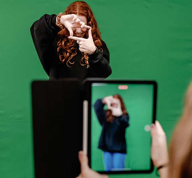 A red haired girl in front of a greenscreen